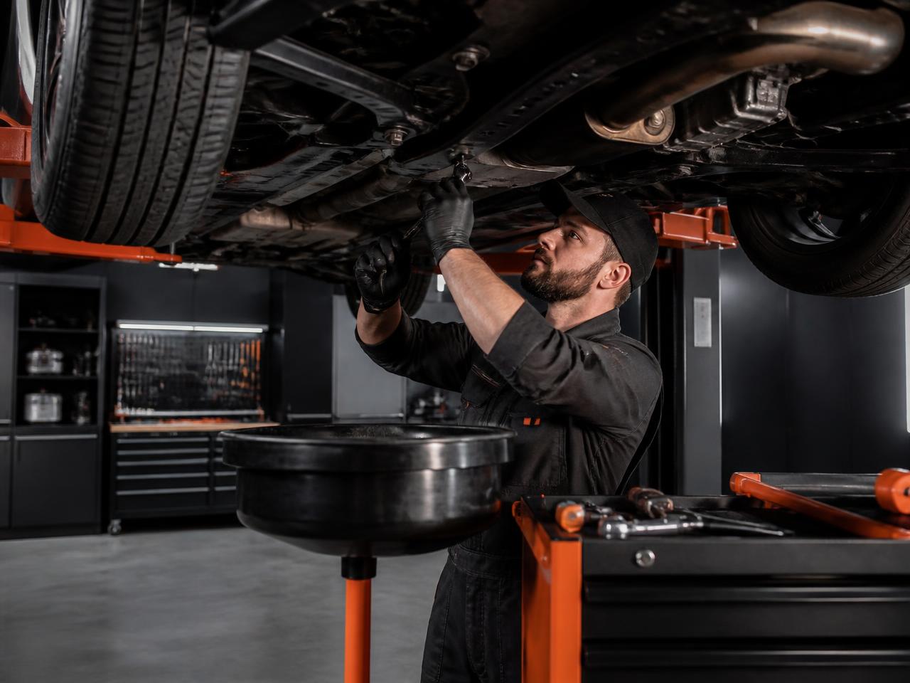 Technician performing an oil change under a lifted vehicle